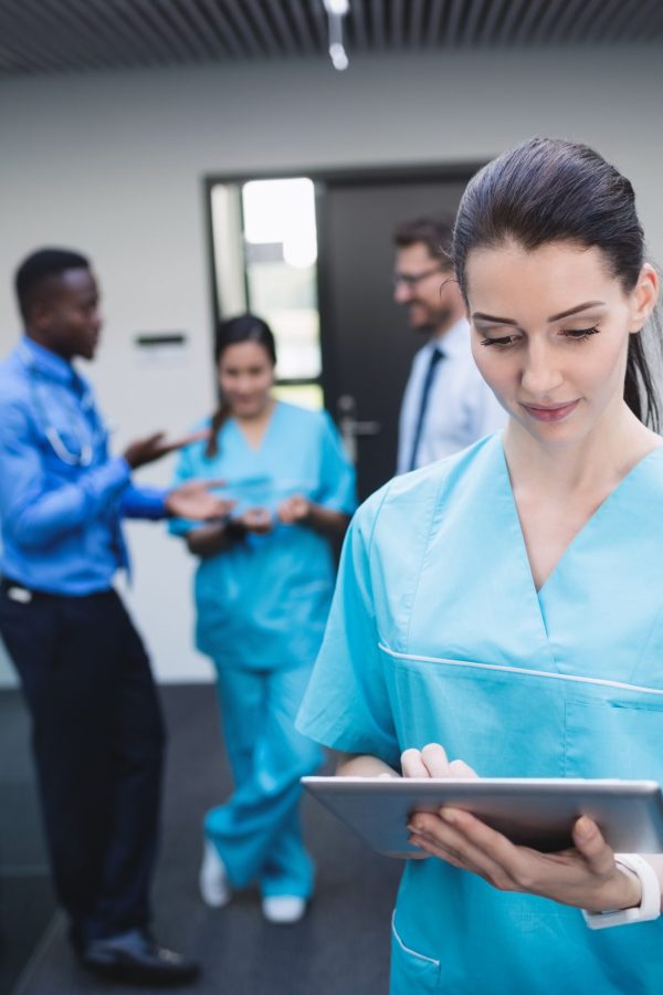 Beautiful nurse using digital tablet in hospital corridor